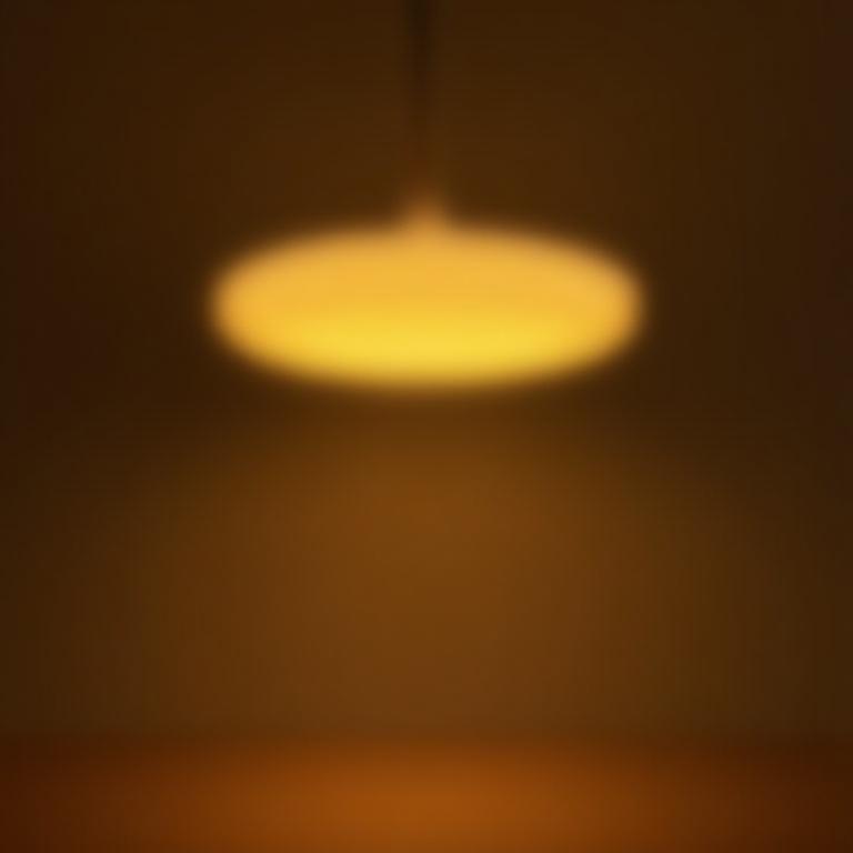 En sirkulær pendellampe med en varm, gyllen glød.